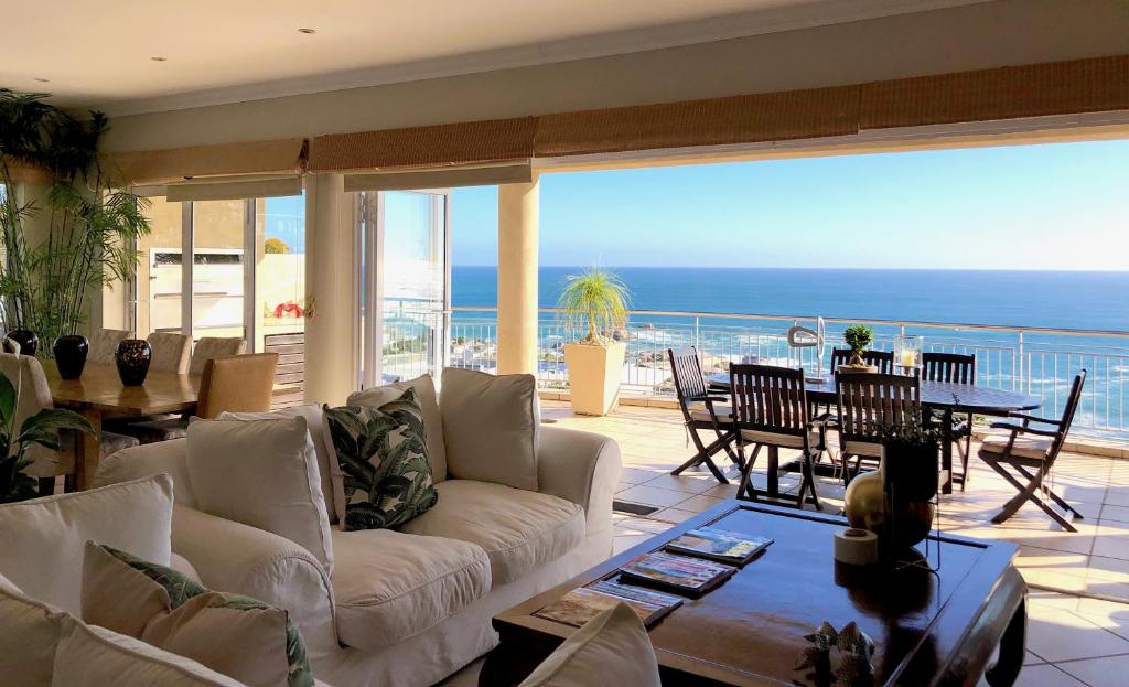 a living room with a couch and a table with a view of the ocean at 3 On Camps Bay in Cape Town