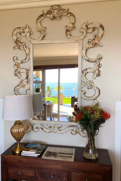 a mirror on a wall next to a table with a lamp at 3 On Camps Bay in Cape Town