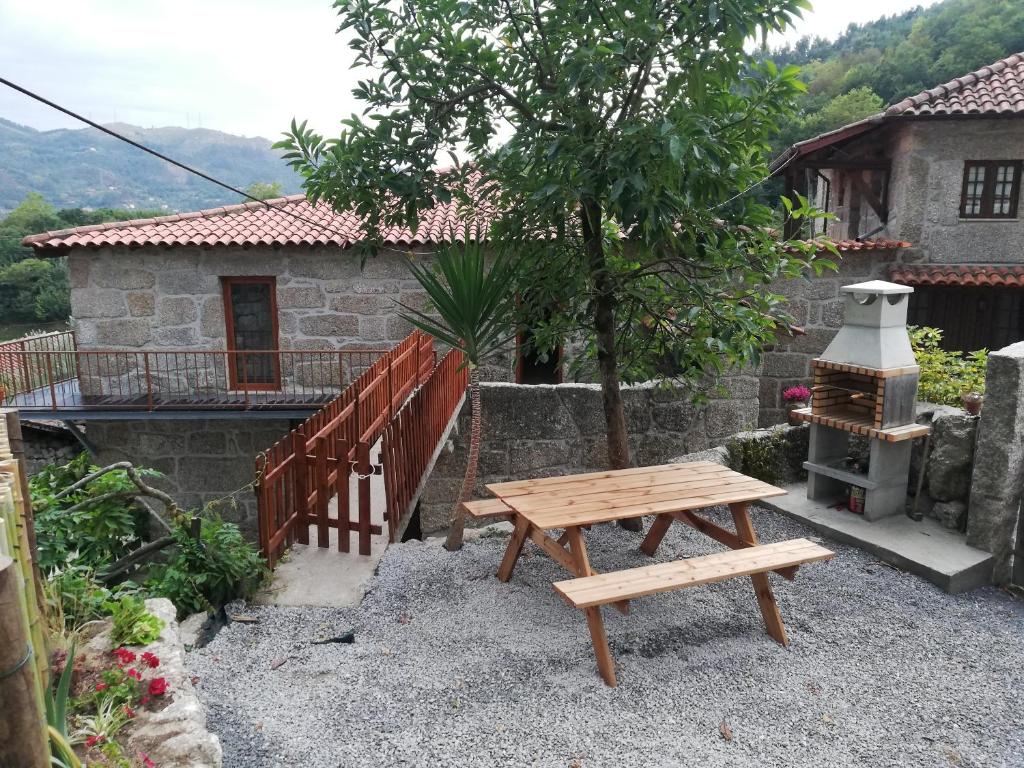 a wooden picnic table in front of a house at Casa Sambinho Gerês in Rio Caldo