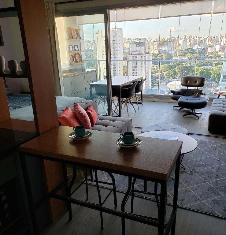 een woonkamer met een salontafel en uitzicht op de stad bij Moderno Oca Moema in Sao Paulo