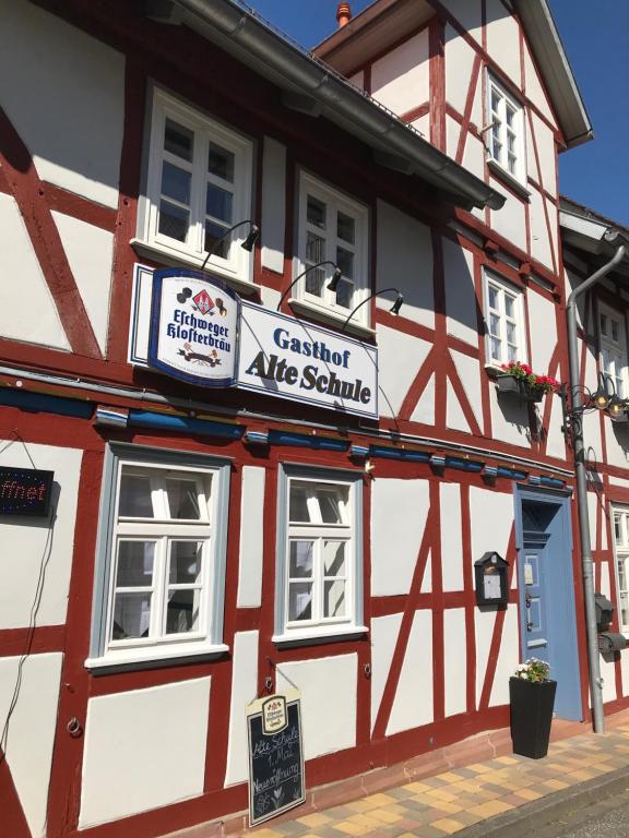 un bâtiment rouge et blanc avec un panneau sur celui-ci dans l'établissement Alte Schule Niederdünzebach, à Eschwege