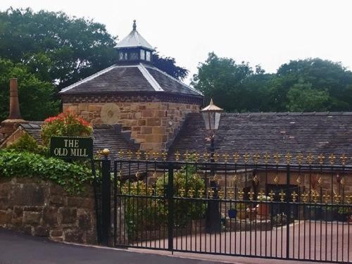 ein altes Gebäude mit einem Schild am Zaun in der Unterkunft The Old Mill and Cottage in Matlock