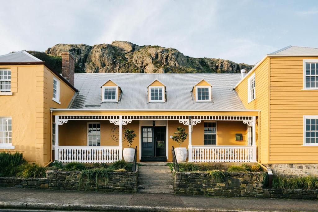 a yellow house with a mountain in the background at Ship Inn Stanley in Stanley