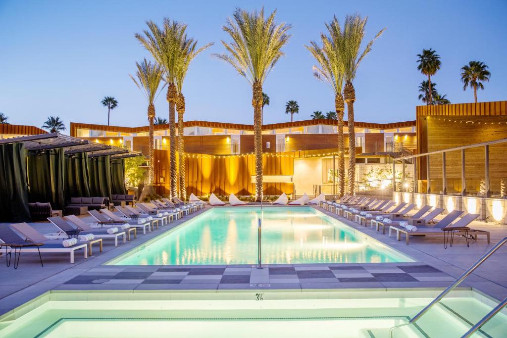 a swimming pool with lounge chairs and palm trees at ARRIVE Palm Springs - Adults Only in Palm Springs