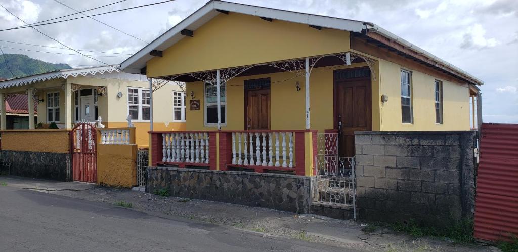 uma casa amarela com uma cerca vermelha à frente. em Roseau Hostel & Beach Front Property em Roseau