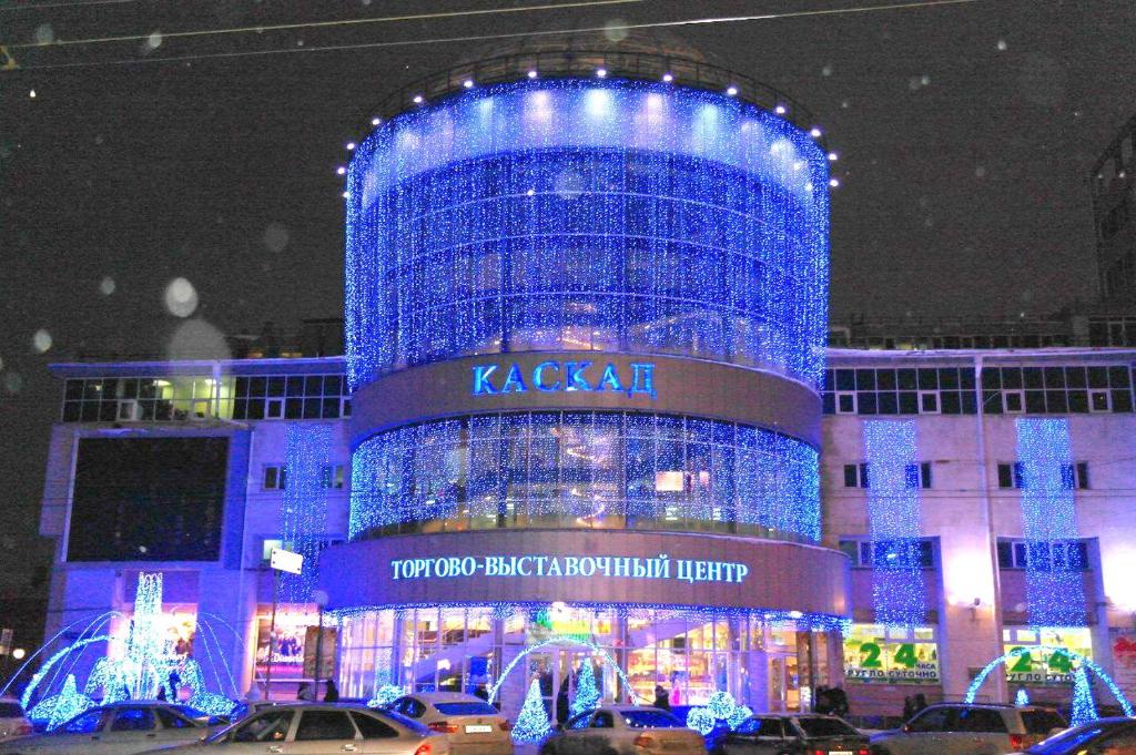 オムスクにあるКАСКAД аpartment na Karla Marksa 2-х комнатная квартираの夜間の青い照明が点灯する大きな建物