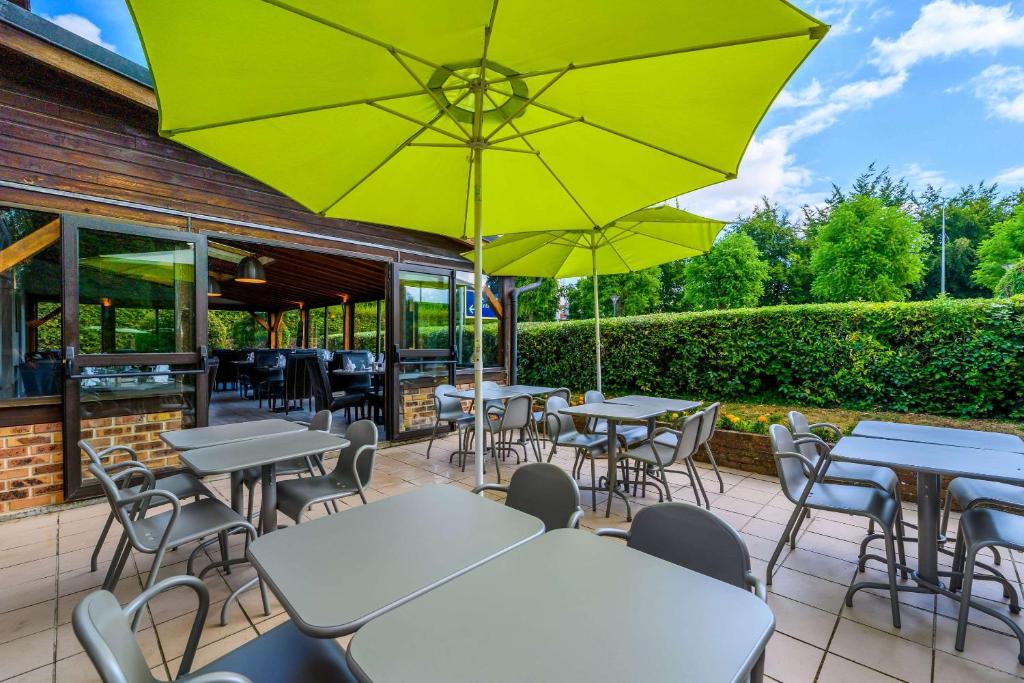a patio with tables and chairs and umbrellas at Comfort Hotel Evreux in Évreux