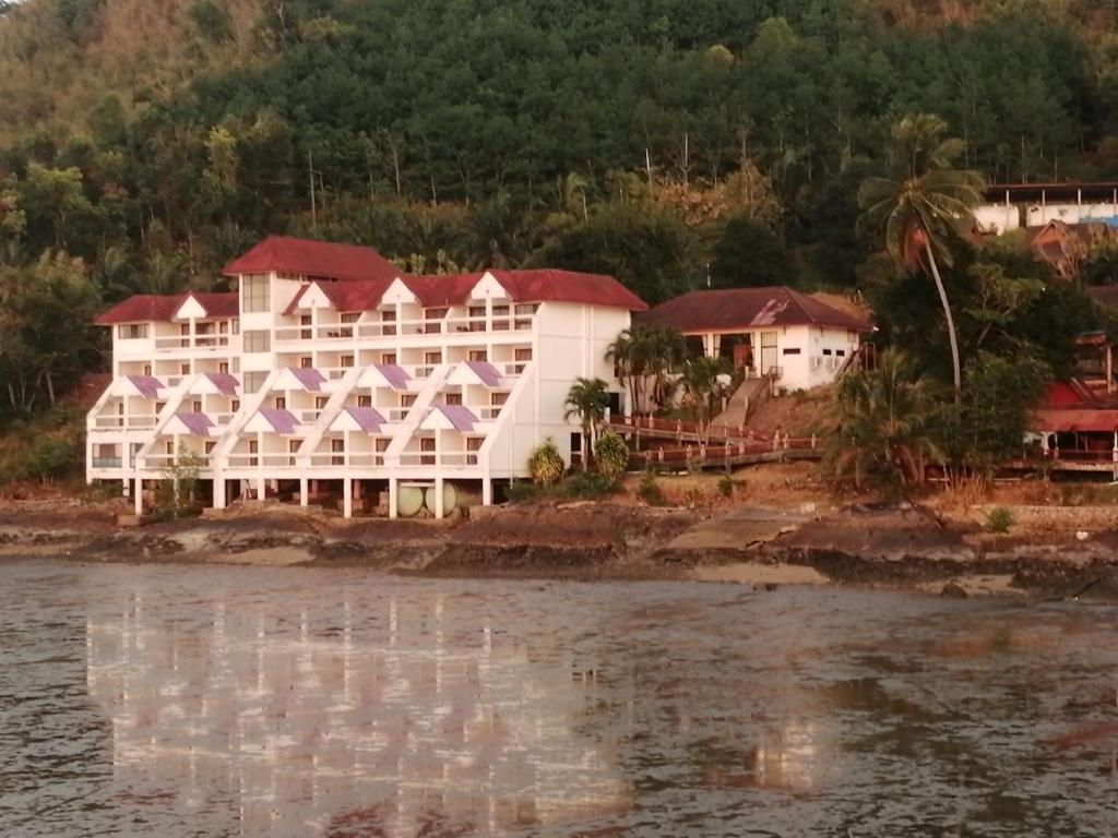 un grand bâtiment blanc sur le côté de l'eau dans l'établissement Jansom Beach Resort, à Ranong