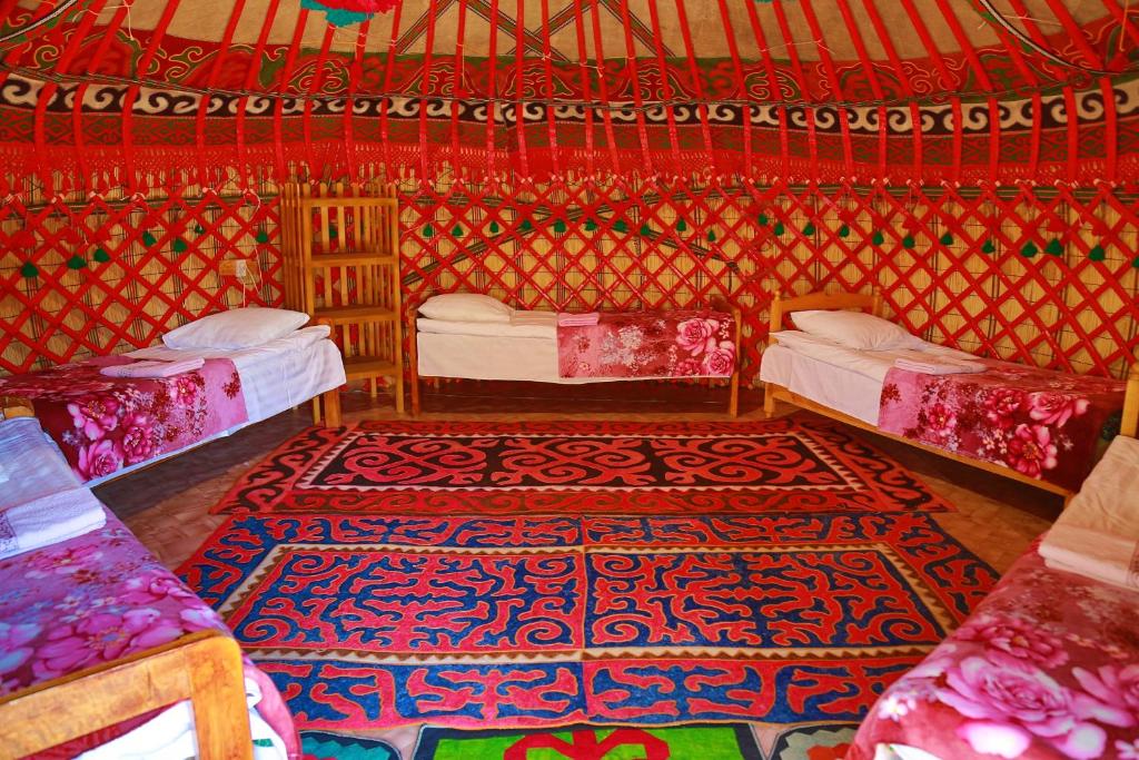 a room with two beds and a rug at Happy Nomads Yurt Camp & Hostel in Karakol