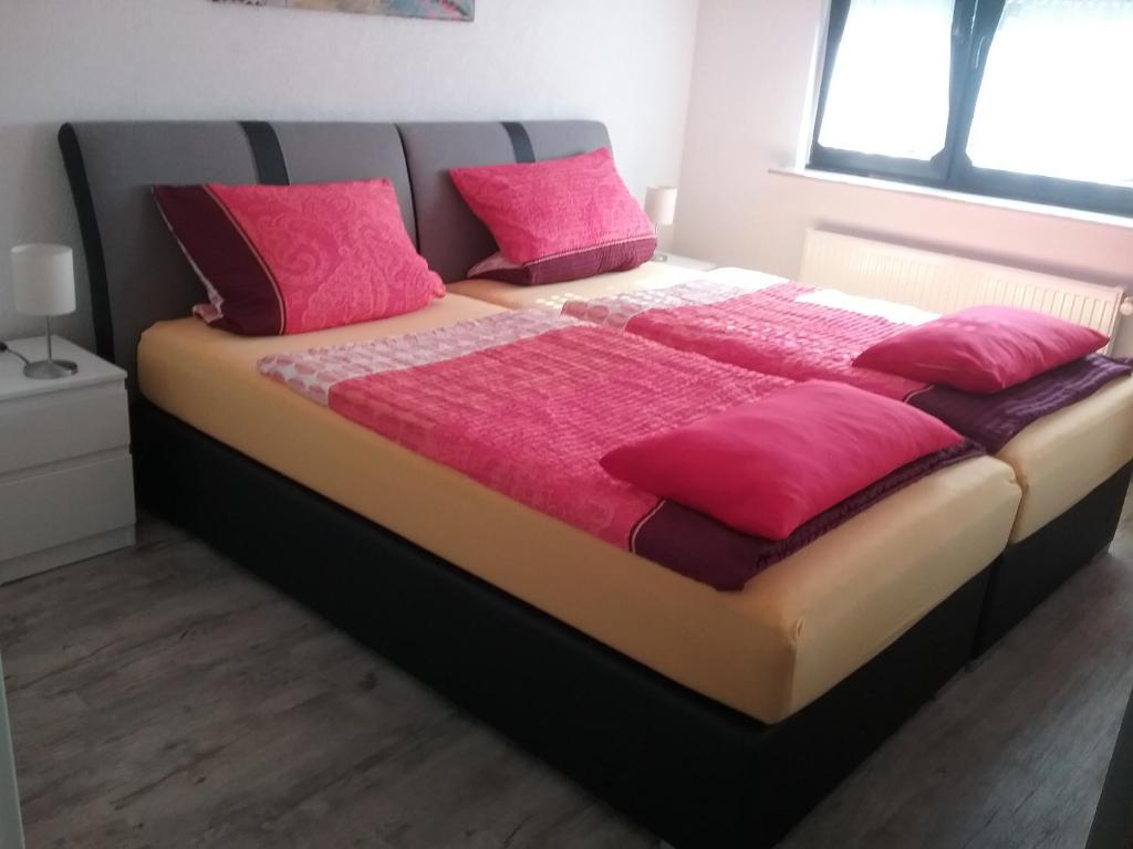 a large bed with pink pillows in a bedroom at Schöne zwei Zimmer Wohnung in Walldorf