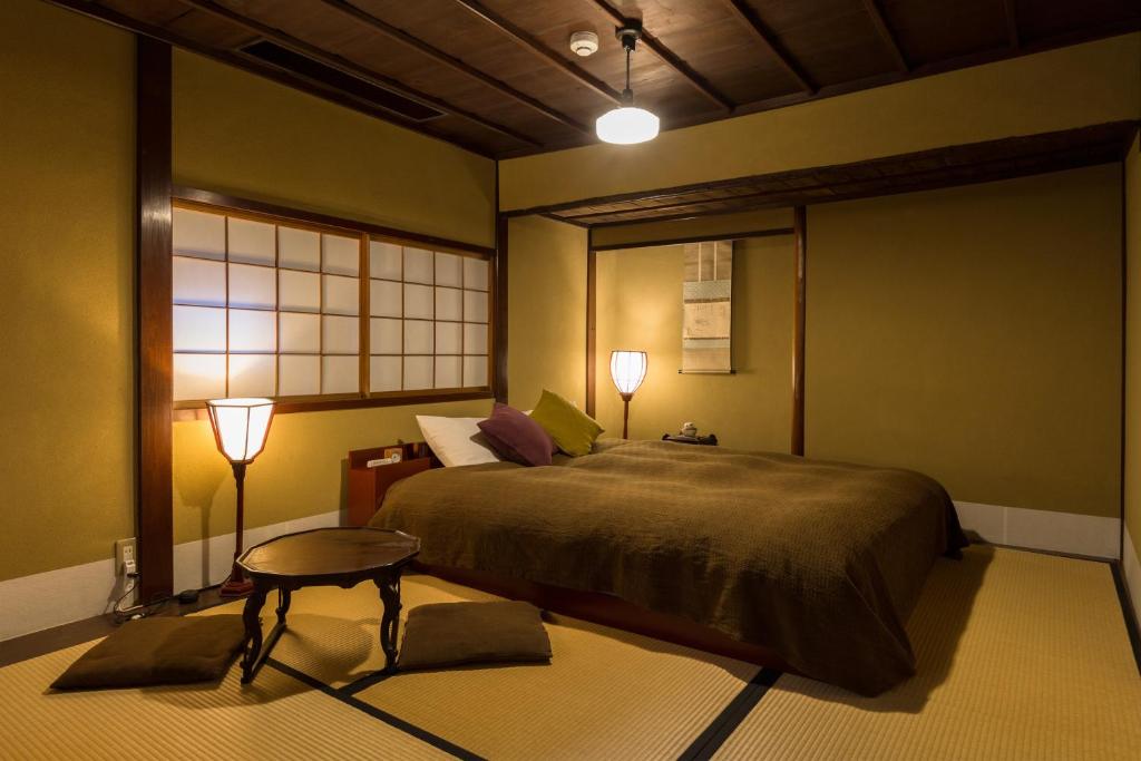 a bedroom with a bed and a table and two lamps at Machiya Kanazawa Kikunoya in Kanazawa