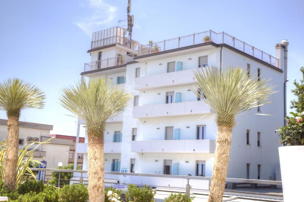 a white building with palm trees in front of it at Hotel Il Caminetto in Porto San Giorgio
