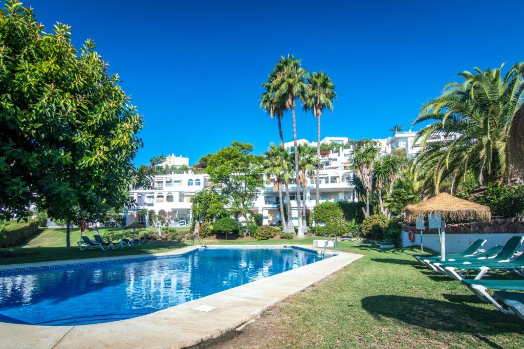 una piscina con palmeras y edificios en appartement gelegen aan de golfbaan op La Quinta Benahavis Marbella, en Benahavís