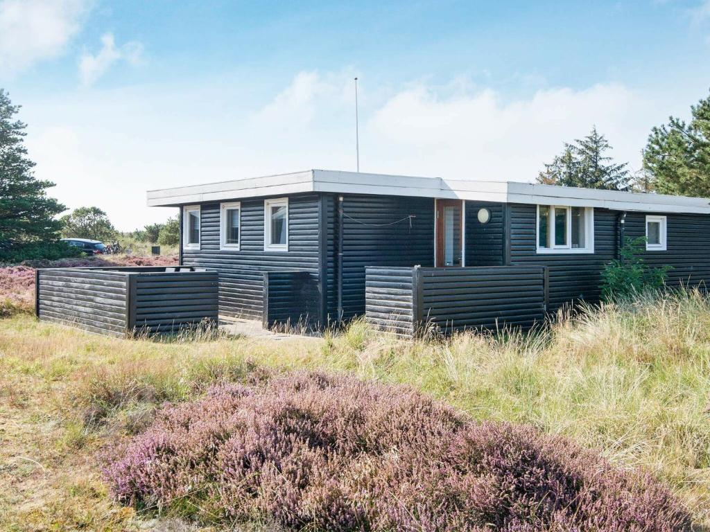 une maison modulaire noire dans un champ dans l'établissement 4 person holiday home in Fan, à Fanø