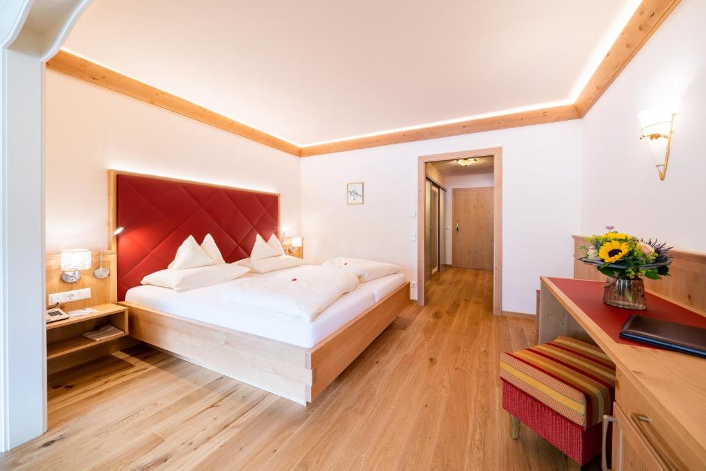 a bedroom with a large bed with a red headboard at Thermenwelt Hotel Pulverer in Bad Kleinkirchheim