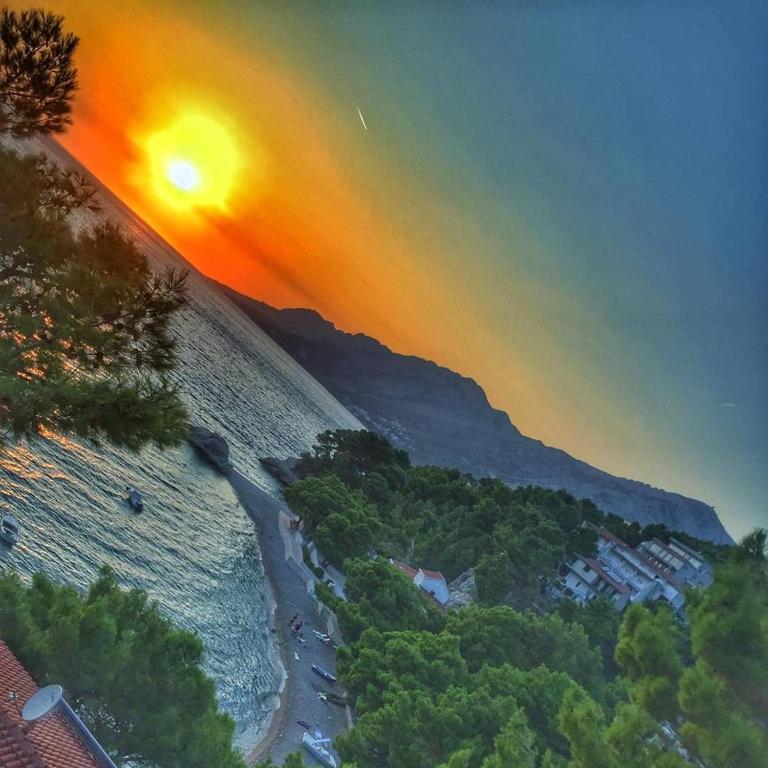 a view of a beach with the sun setting over the water at Villa Luka in Brela