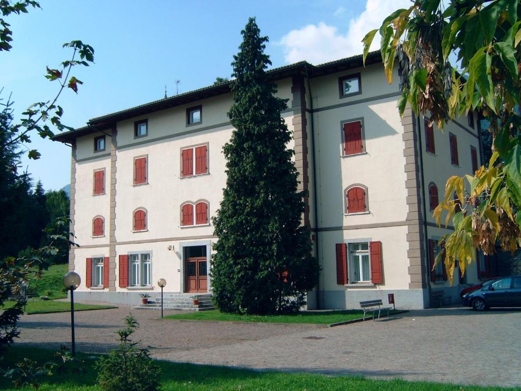 un gran edificio con un árbol delante en Hotel Villa Flora, en Roncegno