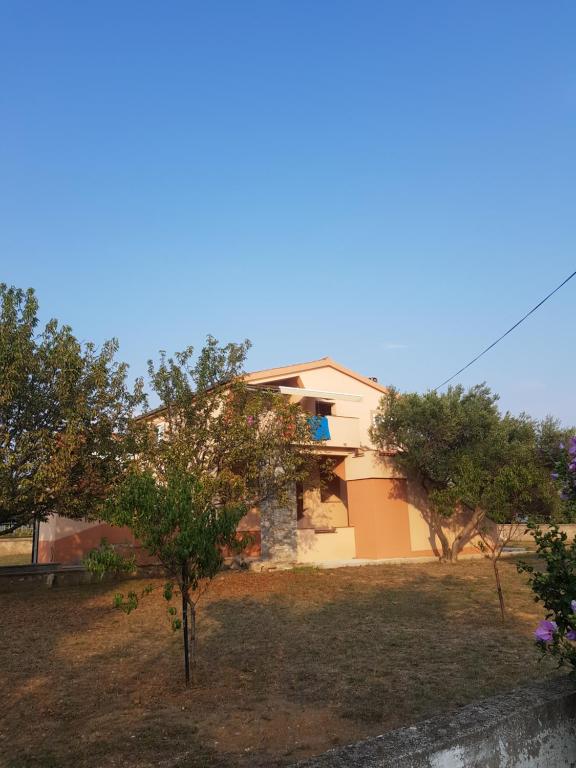 une maison avec des arbres devant une cour dans l'établissement Apartment Leonardo, à Vrsi