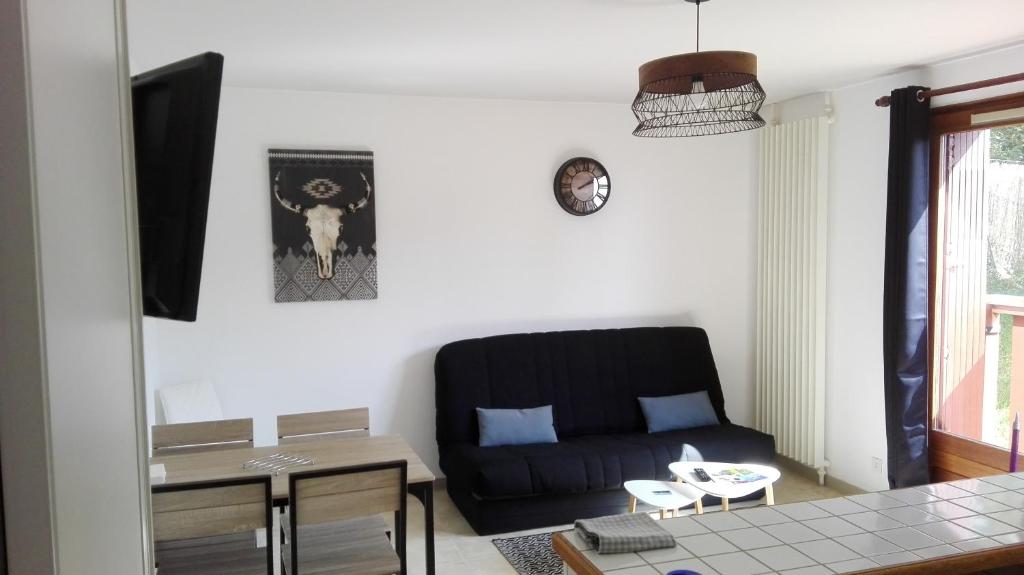 a living room with a black couch and a table at L'appart de lônes in Hauteville-Lompnes