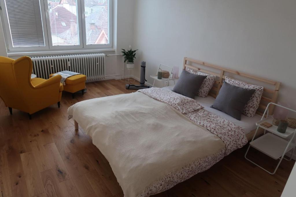 a bedroom with a large bed and a yellow chair at Luxurious apartment 3 min walk to city center - snack, beverages included in price in Spišská Nová Ves