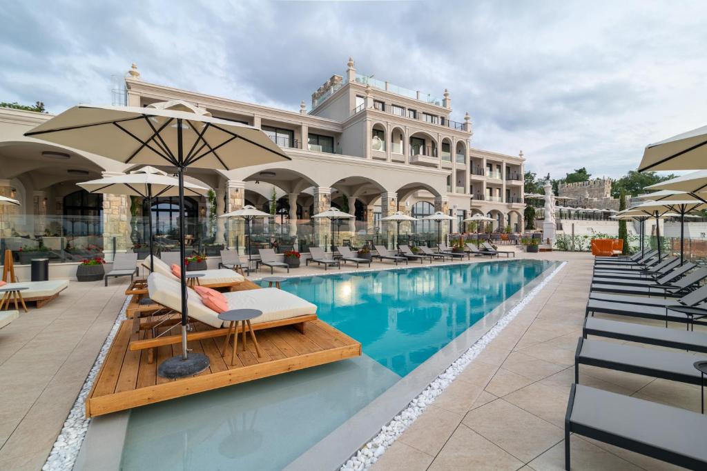 una piscina en un hotel con sillas y sombrillas en Villa Chinka by Astor Garden Hotel - Adults Only, en Saints Constantine and Helena