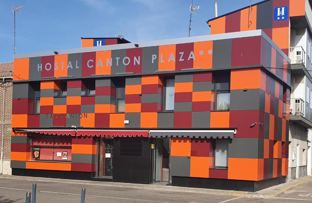 un bâtiment coloré avec un panneau sur son côté dans l'établissement Hostal Canton Plaza, à Hospital de Órbigo