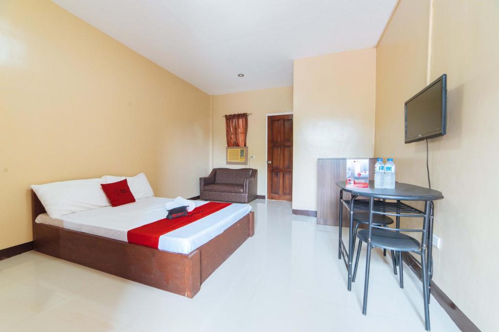 a bedroom with a bed and a desk and a television at RedDoorz @ Lagao General Santos in General Santos