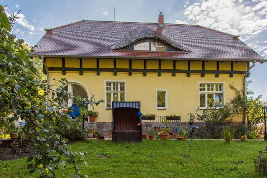 a yellow house with a black roof at Dünenmeisterei in Koserow