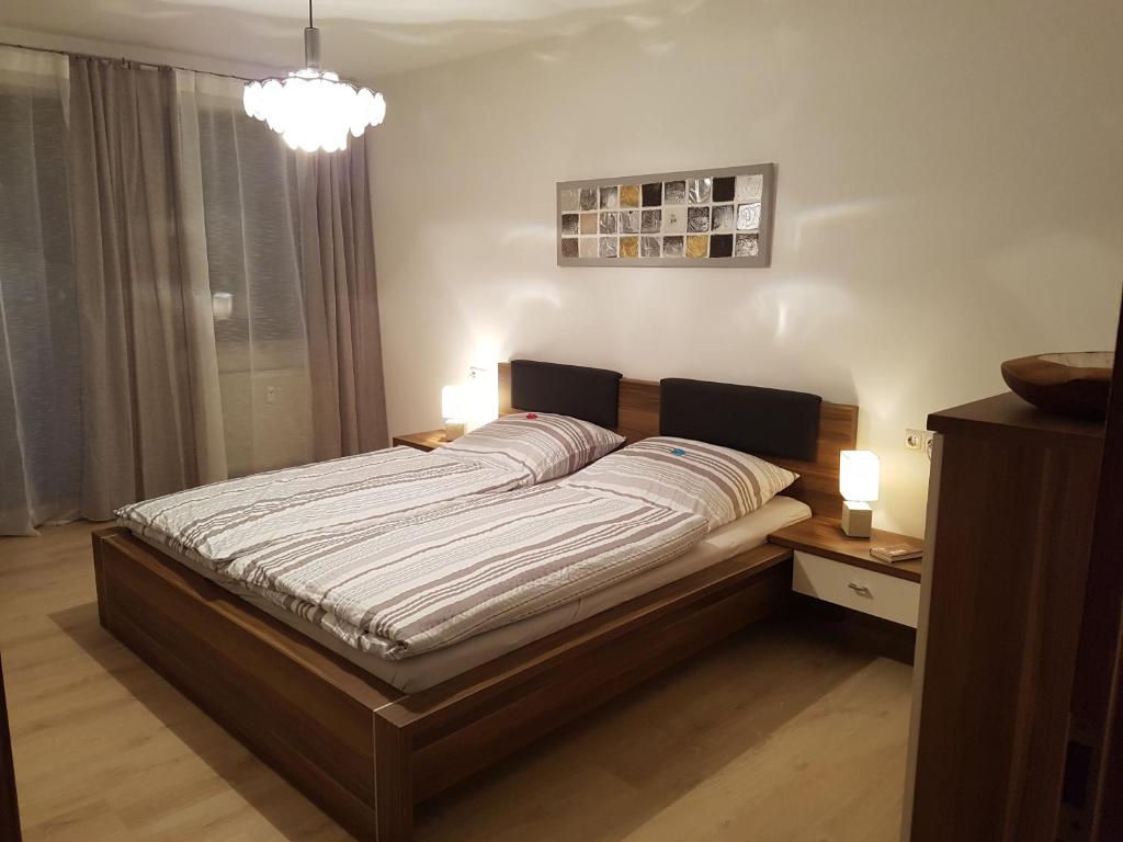 Cama grande en habitación con lámpara en Andys Ferienwohnung, en Neustadt an der Waldnaab