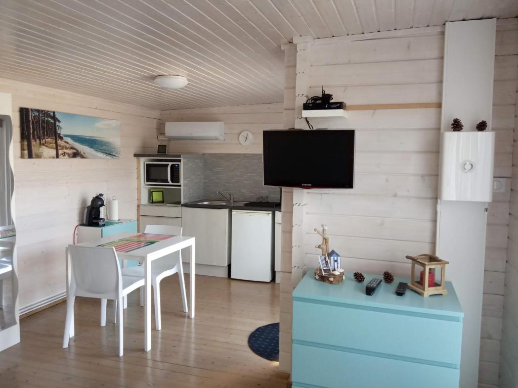 cocina con mesa y TV en la pared en AGREABLE PETIT CHALET, en Camarsac