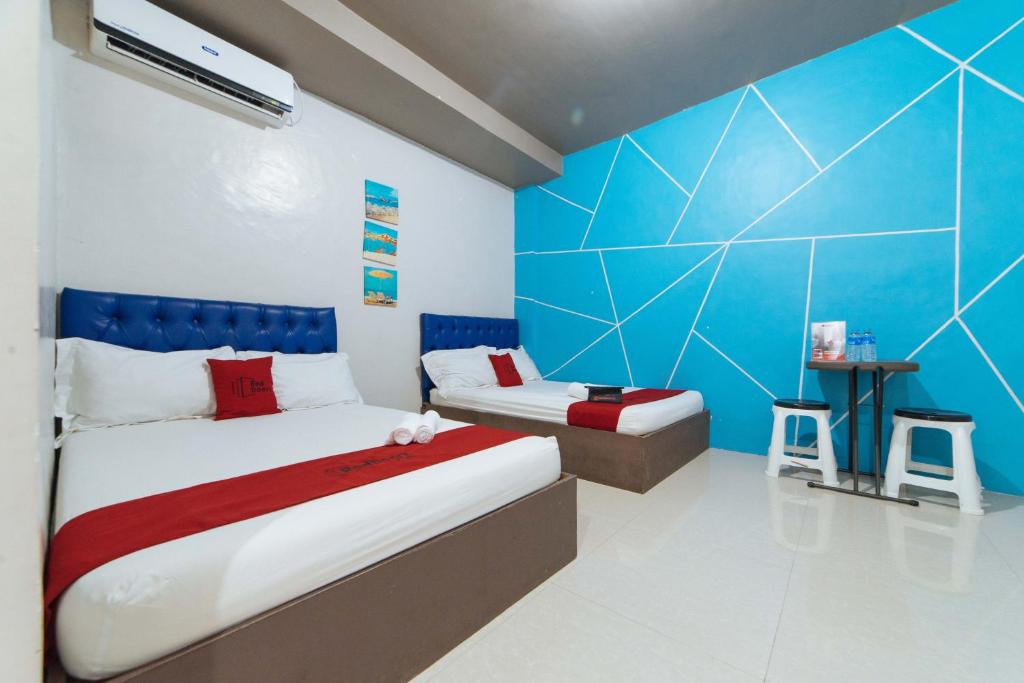 a bedroom with two beds and a blue wall at RedDoorz @ Aparente Gensan in General Santos