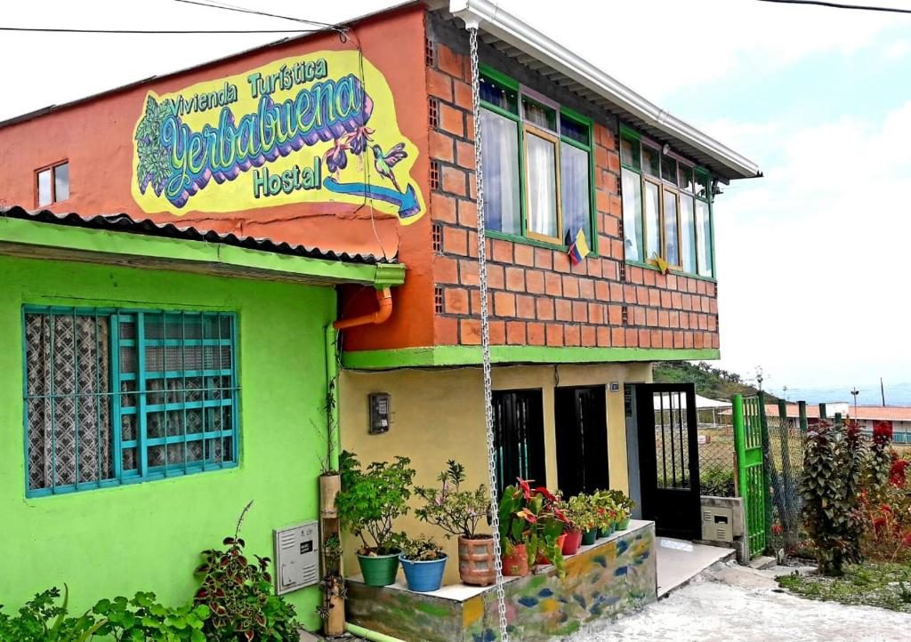 a building with a sign on the side of it at Vivienda Turistica Yerbabuena in Filandia