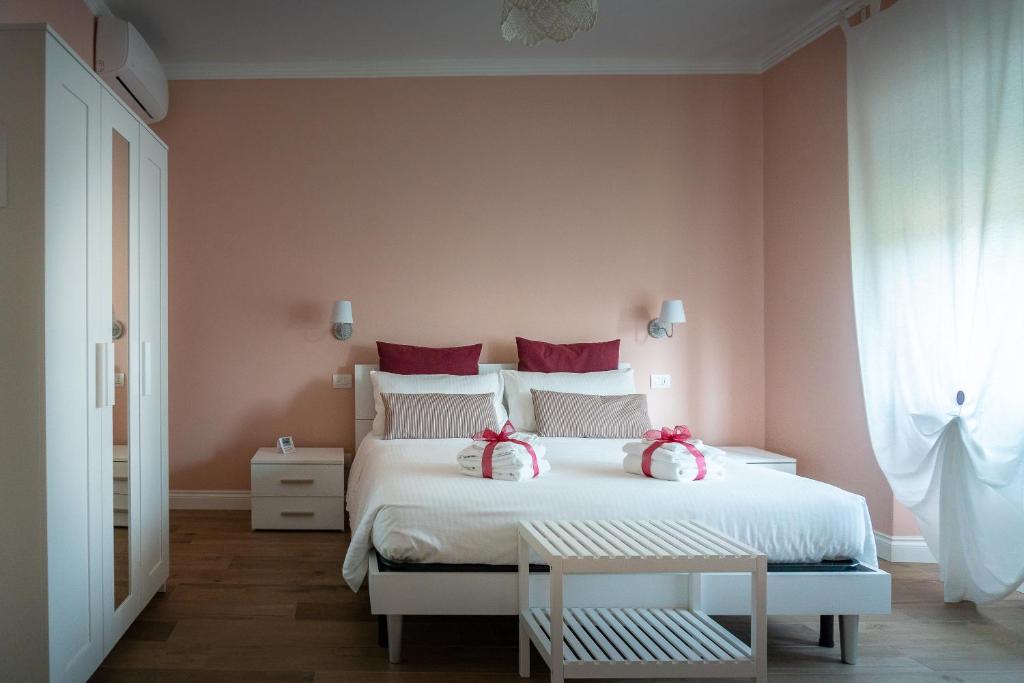 una camera da letto con un grande letto bianco con cuscini rossi di La Rosa Tra I Laghi B&B a Meina