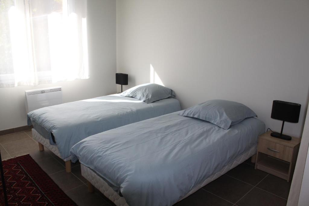 two beds in a white bedroom with a window at Villa Caramel in Saint-Quentin-la-Poterie