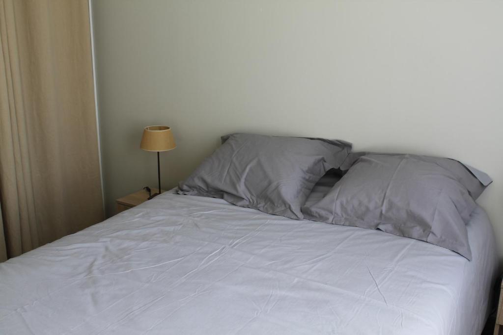 a white bed with two pillows on top of it at Villa Caramel in Saint-Quentin-la-Poterie