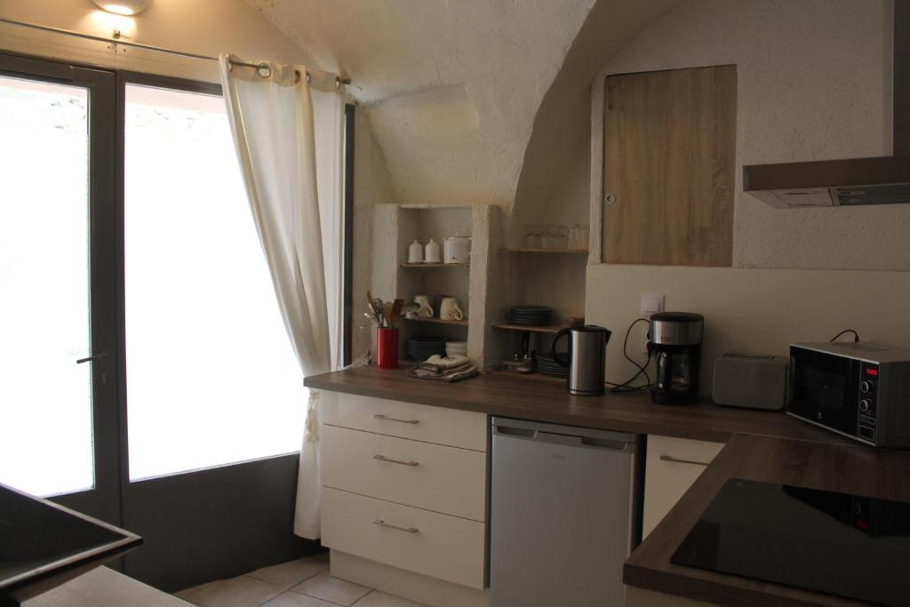 eine Küche mit weißen Schränken und einer Arbeitsplatte in der Unterkunft maison de village in Saint-Quentin-la-Poterie