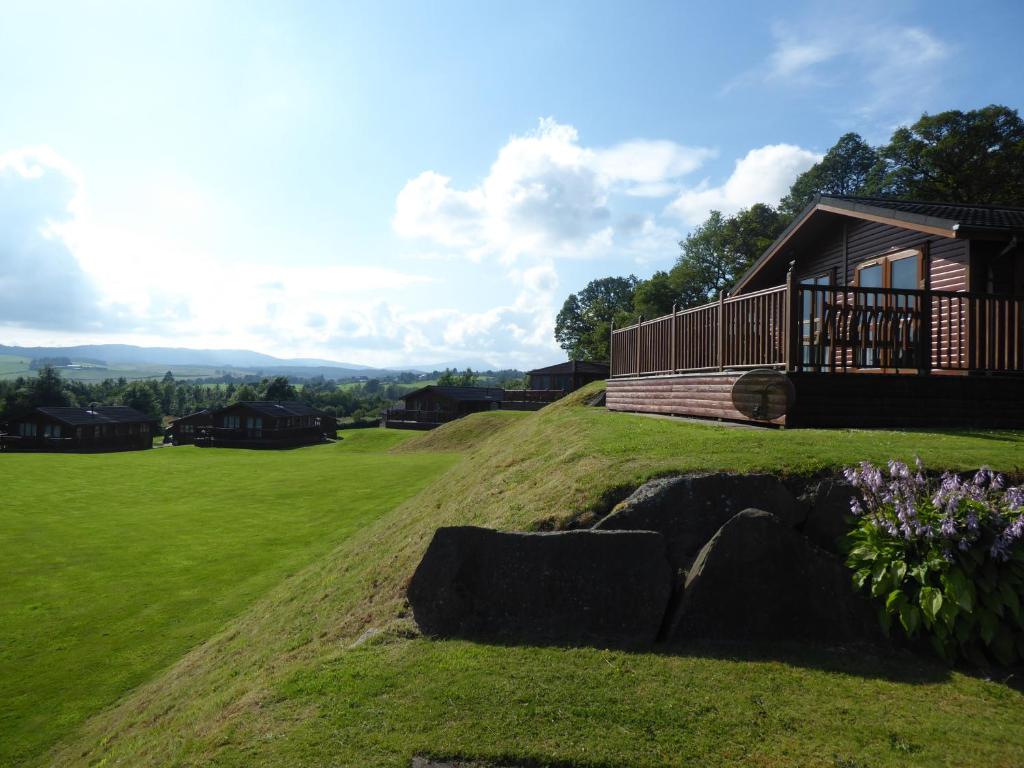 a house on top of a grassy hill with rocks at Trossachs Holiday Park in Drymen