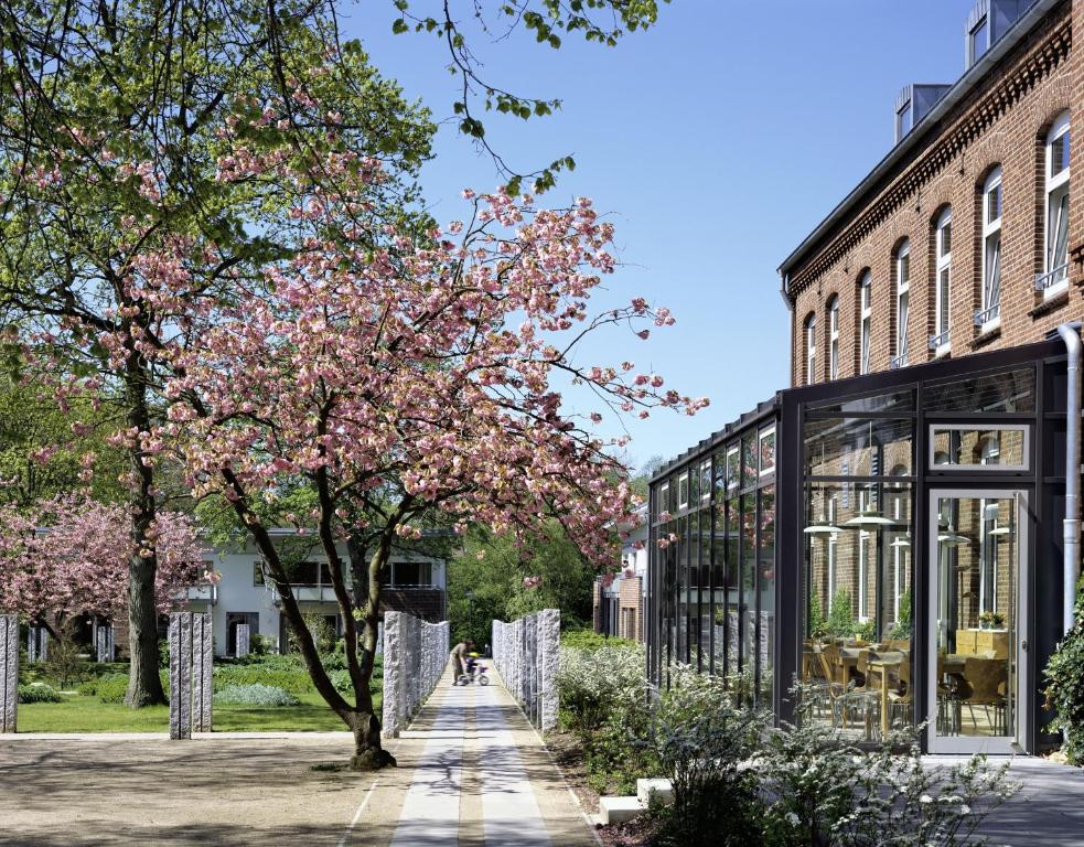 Breklum的住宿－Christian Jensen Kolleg und Gästehäuser，一座建筑物前有粉红色花的树