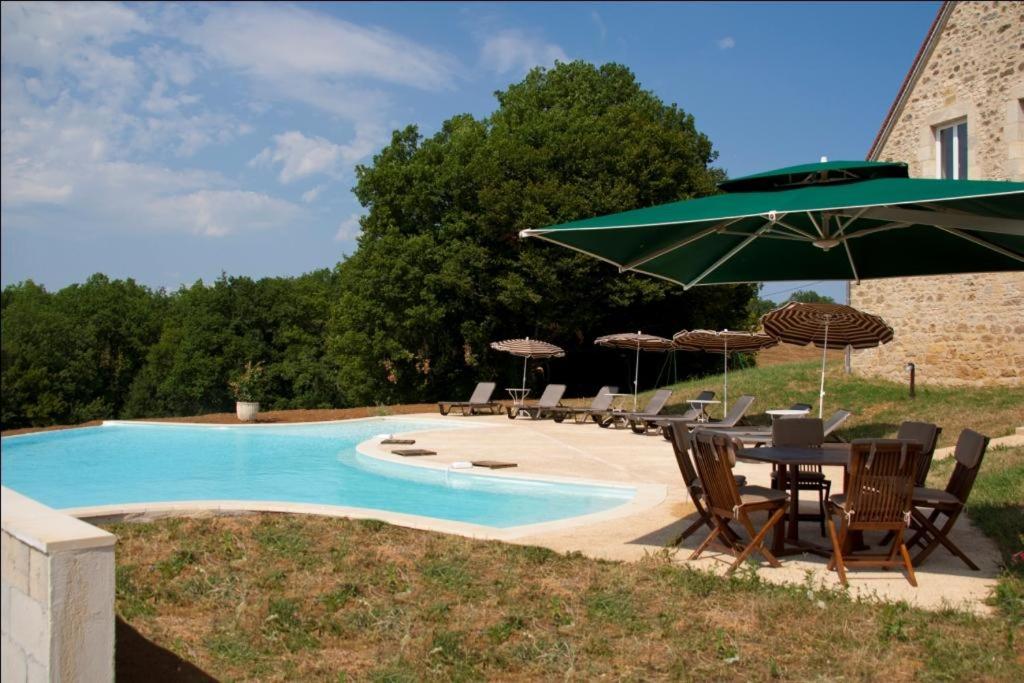 a table with an umbrella next to a swimming pool at Domaine de Janis & Spa in Le Vigan