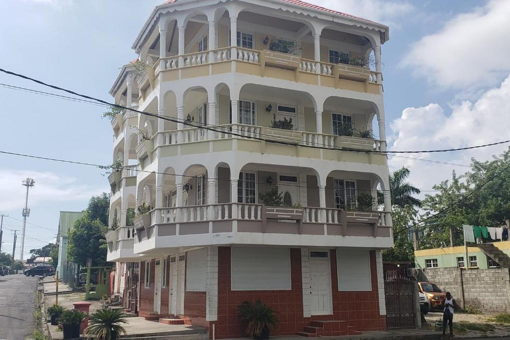 ein hohes weißes Gebäude mit Balkonen auf einer Straße in der Unterkunft Unit 2 Private Apartment - Roseau in Roseau