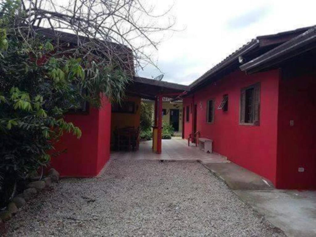 a red house with a pathway next to a building at Pousada da Tom-Ubatuba Perequê-Açu in Ubatuba
