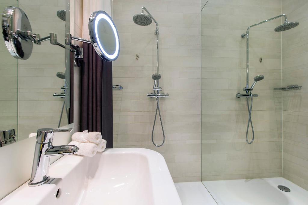 a bathroom with a shower, sink, and mirror at Amsterdam Canal Hotel in Amsterdam