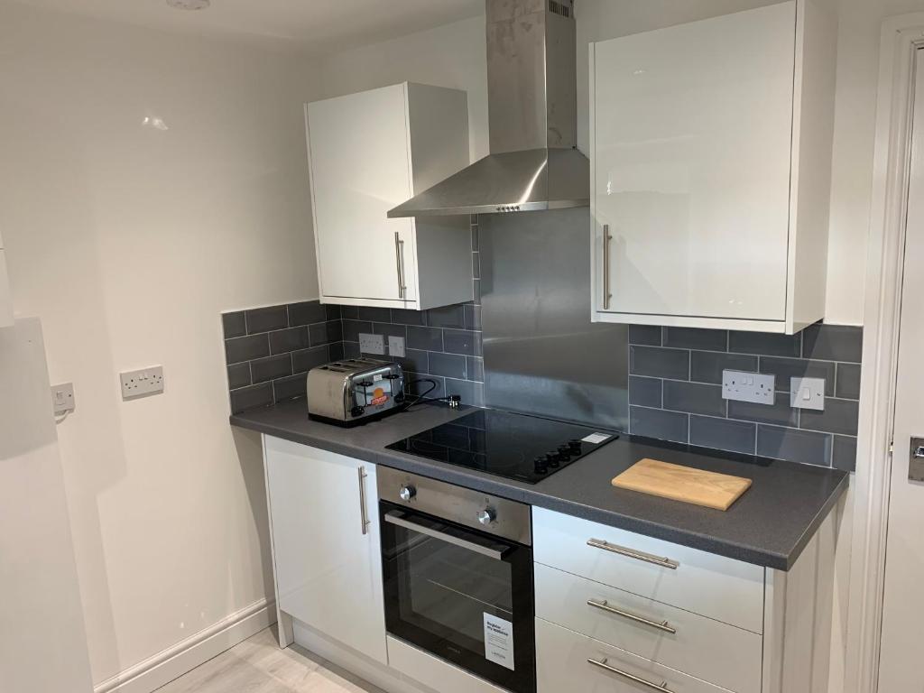 uma cozinha com armários brancos e um balcão preto em sark house Apartment Chorlton manchester em Manchester