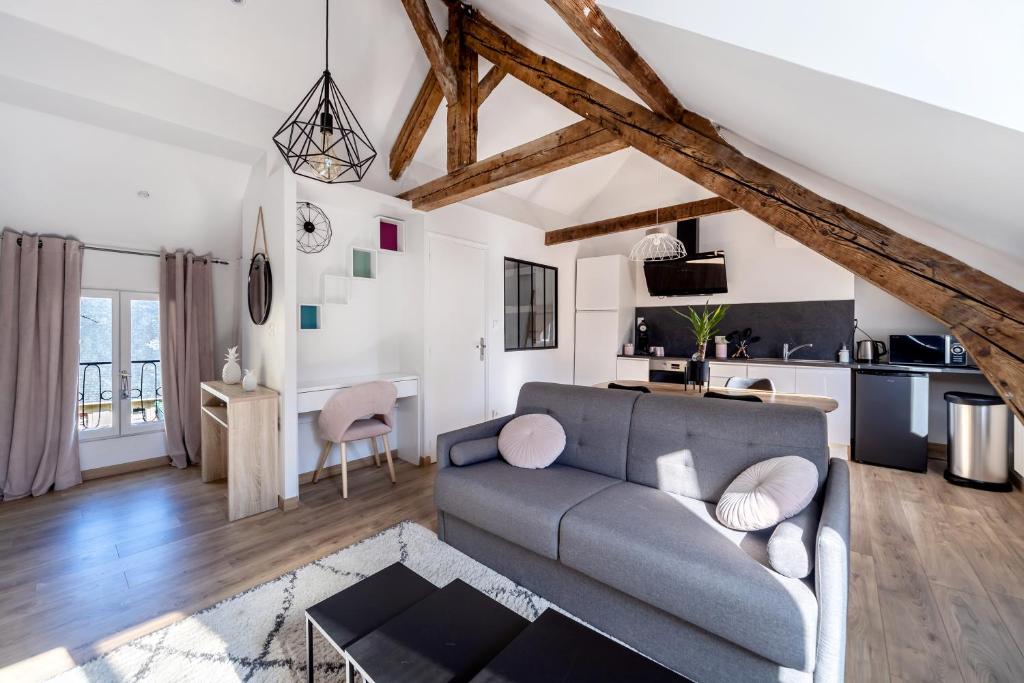 a living room with a gray couch and a kitchen at Appartement cosy*** Centre historique Dieppe - rue piétonne à 200m de la plage in Dieppe