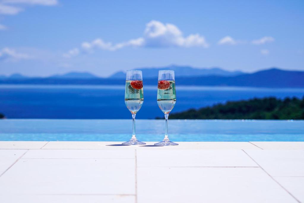 zwei Weingläser auf einem Tisch neben einem Pool in der Unterkunft Villa Shiraz in Selca