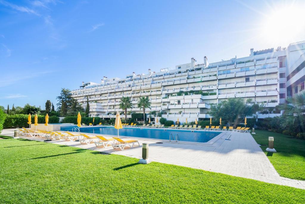 un gran edificio con una piscina con sillas y un edificio en Apartamento dentro da Marina de Vilamoura, en Vilamoura