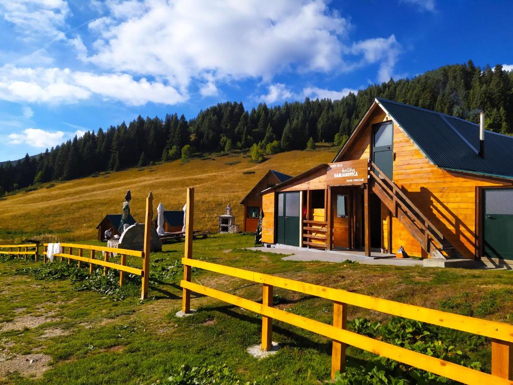 a wooden cabin on a hill with a fence at Eko Katun Damjanovic - Bjelasica in Mojkovac