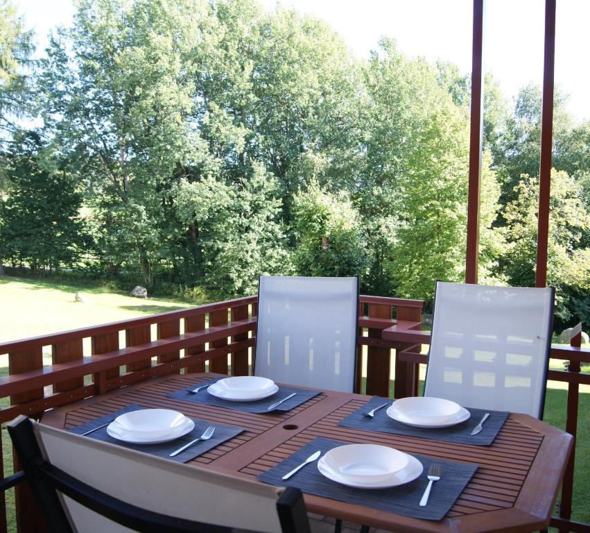 - une table en bois avec des assiettes et des chaises blanches sur une terrasse couverte dans l'établissement Ferienwohnung Schwarzwaldlust, à Schluchsee