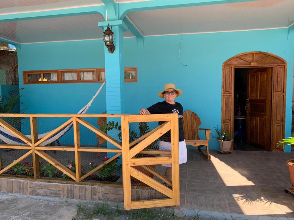 un hombre sentado en una silla frente a una casa azul en Hostal Mi Castillo, en Mariabé