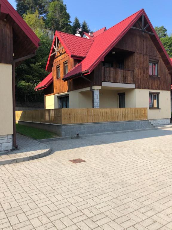 a building with a red roof and a patio at Domek na Jasnej in Muszyna